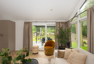 Lichte woonkamer in Doornenburg Lodge Comfort, Veluwepark de Bosgraaf, Nederland, met grote ramen.