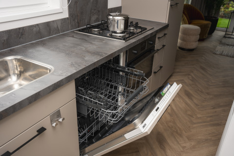 Modern kitchen with open dishwasher and stove at Doornenburg Lodge Comfort, Veluwepark de Bosgraaf, Netherlands.