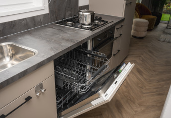 Modern kitchen with open dishwasher and stove at Doornenburg Lodge Comfort, Veluwepark de Bosgraaf, Netherlands.