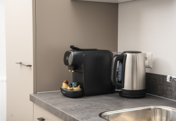 Cafetera moderna y hervidor eléctrico sobre la encimera en Doornenburg Lodge Comfort en Veluwepark de Bosgraaf.