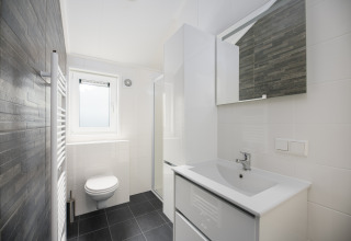 Moderne badeværelse på Doornenburg Lodge Comfort, Veluwepark de Bosgraaf, Nederlandene, med hvidt interiør.