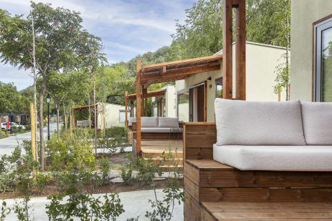 Vista exterior del lodge Mobile home FAMILY en Wecamp Pirineos, España, con terraza y vegetación alrededor.