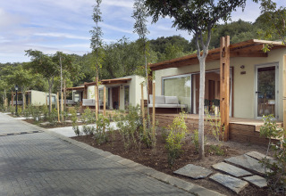Moderne Mobilheime mit Holzveranda und Garten am Wecamp Pirineos Lodge in Spanien bei sonnigem Wetter.