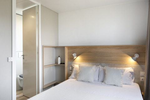 Schlafzimmer im Mobile Home FAMILY XL bei Wecamp Pirineos in Spanien mit Doppelbett und Bad.