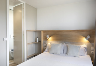 Schlafzimmer im Mobile Home FAMILY XL bei Wecamp Pirineos in Spanien mit Doppelbett und Bad.