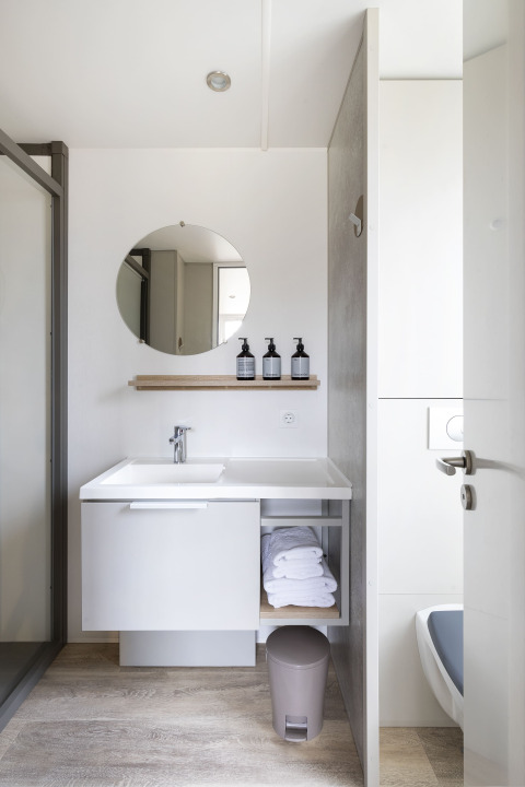 Baño moderno de una Mobile home FAMILY XL en Wecamp Pirineos, España, con lavabo, espejo y toallas.