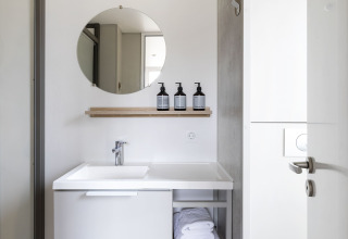 Baño moderno de una Mobile home FAMILY XL en Wecamp Pirineos, España, con lavabo, espejo y toallas.