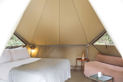 Innenansicht des Bell Tents bei Wecamp Pirineos in Spanien mit Bett, Sofa und Tisch im Safarizelt.