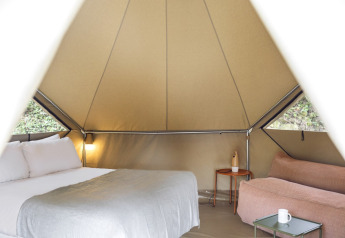 Interior de la tienda Bell Tent en Wecamp Pirineos, España, con cama, sofá y mesa en un tipi safari.