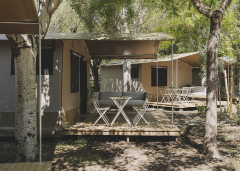Safari telt med træterrasse og havemøbler på Wecamp Pirineos, omgivet af træer i Spanien.