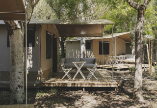 Safari telt med træterrasse og havemøbler på Wecamp Pirineos, omgivet af træer i Spanien.