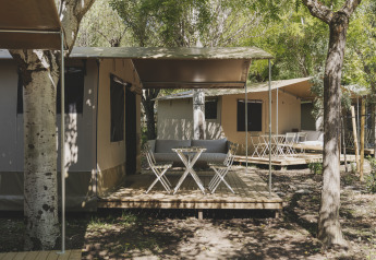 Safari telt med træterrasse og havemøbler på Wecamp Pirineos, omgivet af træer i Spanien.