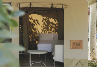 Safari-telt 'Cottage Family Tent' hos Wecamp Pirineos i Spanien, med seng og udendørs siddeplads.