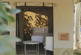 Safari-telt 'Cottage Family Tent' hos Wecamp Pirineos i Spanien, med seng og udendørs siddeplads.