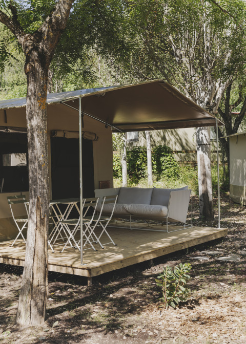 Safari telt kaldet Cottage Family Tent på Wecamp Pirineos i Spanien, med terrasse, stole og sofa i naturen.