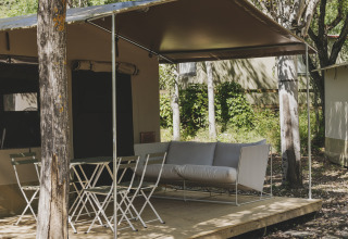 Safari telt kaldet Cottage Family Tent på Wecamp Pirineos i Spanien, med terrasse, stole og sofa i naturen.