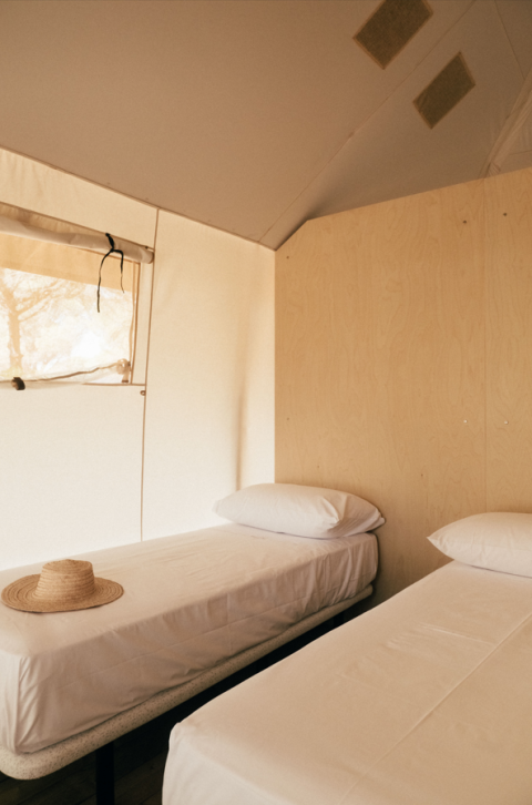 Twee eenpersoonsbedden met witte lakens in een safaritent van Lodge Family bij Wecamp Cádiz in Spanje.