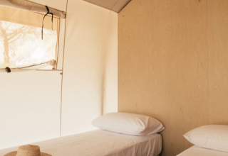 Twee eenpersoonsbedden met witte lakens in een safaritent van Lodge Family bij Wecamp Cádiz in Spanje.