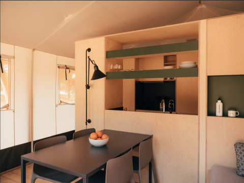 Interior view of a Lodge Family Plus safari tent at Wecamp Cádiz, Spain, with dining table and kitchen area.