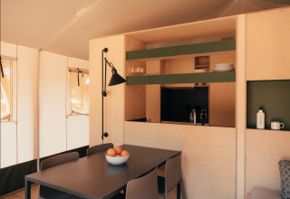 Interior view of a Lodge Family Plus safari tent at Wecamp Cádiz, Spain, with dining table and kitchen area.