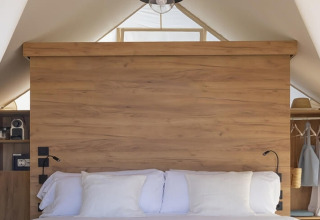 Cozy bed with white bedding inside a safari tent, Glamping Couple, Wecamp Cádiz, Spain.