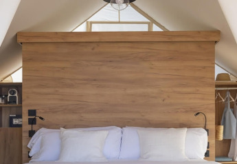 Letto accogliente con biancheria bianca in una tenda safari, Glamping Couple, Wecamp Cádiz, Spagna.