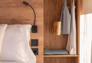 Cozy safari tent interior at Wecamp Cádiz, Spain, with bed, wooden wardrobe, soft lighting and minimal decor.