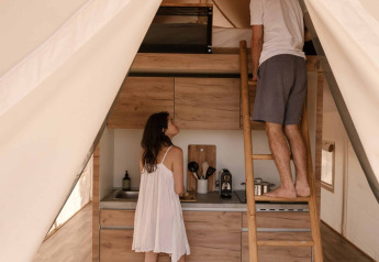 All'interno di una tenda safari Glamping Comfort presso Wecamp Cádiz, Spagna, una coppia in cucina.