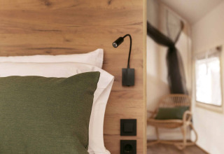 Interieur van een Glamping Comfort safaritent bij Wecamp Cádiz met houten bed, groen kussen en boek.