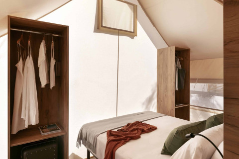 Interieur van een Glamping Comfort-safaristent bij Wecamp Cádiz, Spanje, met bed en houten kasten.