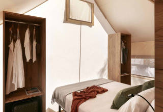 Interieur van een Glamping Comfort-safaristent bij Wecamp Cádiz, Spanje, met bed en houten kasten.