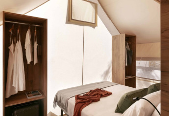 Interno di una tenda safari Glamping Comfort presso Wecamp Cádiz, Spagna, con letto e armadi in legno.