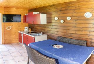 Lyst træinteriør i Blasge Bungalow 1 med lille køkken, spisebord, vægdekorationer og TV i Østrig.