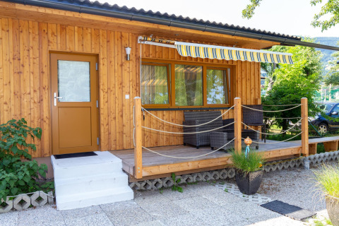 Træbungalow med terrasse, markise og havemøbler ved Blasge Bungalow 1 i Østrig på en solrig dag.