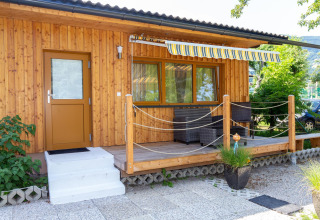Træbungalow med terrasse, markise og havemøbler ved Blasge Bungalow 1 i Østrig på en solrig dag.