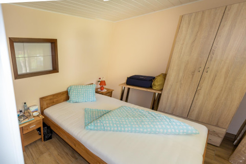 En hyggelig seng i Blasge Bungalow 1, Østrig, med træmøbler og blå-sengetøj på et enkelt værelse.