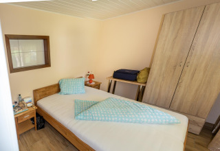 En hyggelig seng i Blasge Bungalow 1, Østrig, med træmøbler og blå-sengetøj på et enkelt værelse.