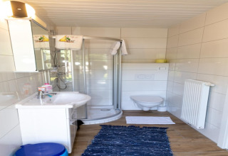Moderne badeværelse i Blasge Bungalow 1 Østrig med brusekabine, væghængt toilet og hvidt interiør.
