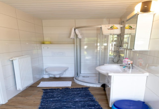 Moderne badeværelse i Blasge Bungalow 1, Østrig, med bruseniche, toilet og hvidt interiør.