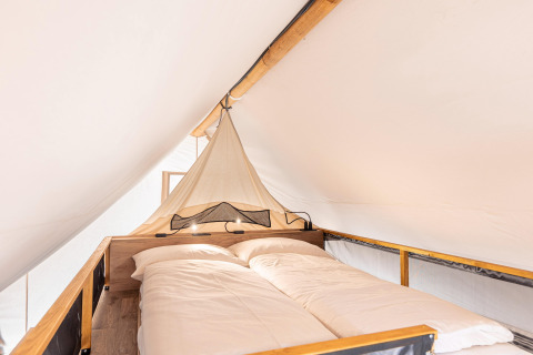 Vista interna di un letto accogliente in una tenda safari a Chalets & Glamping Nassfeld 5 in Austria.