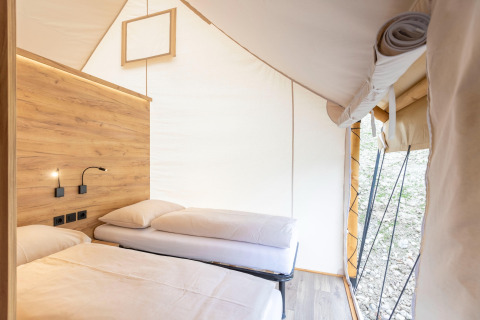 Interno di una tenda safari con due letti e dettagli in legno presso Chalets & Glamping Nassfeld 5 in Austria.