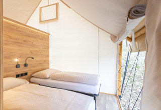 Interno di una tenda safari con due letti e dettagli in legno presso Chalets & Glamping Nassfeld 5 in Austria.