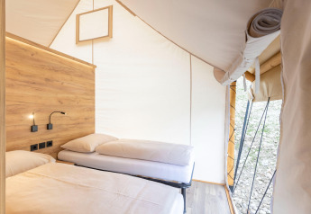 Interieur van een safaritent met twee bedden en houtaccenten bij Chalets & Glamping Nassfeld 5 in Oostenrijk.
