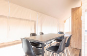 Eettafel met zes zwarte stoelen in een lichte safaritent bij Chalets & Glamping Nassfeld 6, Oostenrijk.