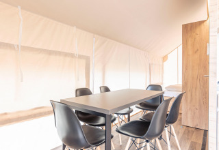 Tavolo da pranzo con sei sedie nere in una tenda safari luminosa, Chalets & Glamping Nassfeld 6, Austria.