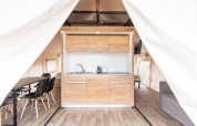 Moderne safaritent met houten keuken en eettafel bij Chalets & Glamping Nassfeld in Oostenrijk.