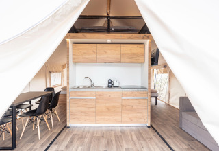 Interno di tenda safari moderna con cucina e tavolo da pranzo nei Chalets & Glamping Nassfeld, Austria.