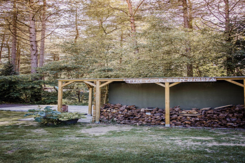 Een houtopslag met haardhout in een bosrijke omgeving bij een glamping accommodatie.