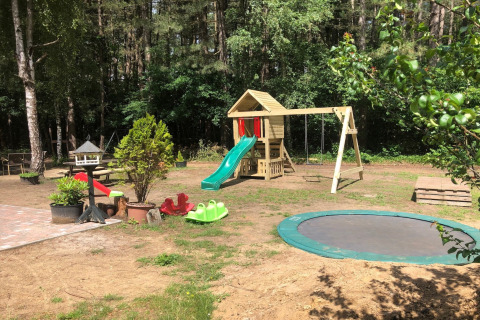 Parco giochi nel giardino dello chalet 'Vlaamse gaai' in Belgio con scivolo, altalene e trampolino.