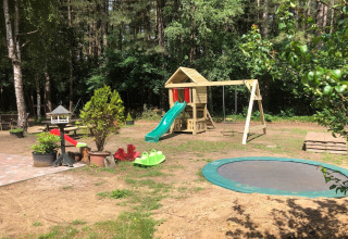 Aire de jeux au jardin du chalet 'Vlaamse gaai' en Belgique avec toboggan, balançoires et trampoline.